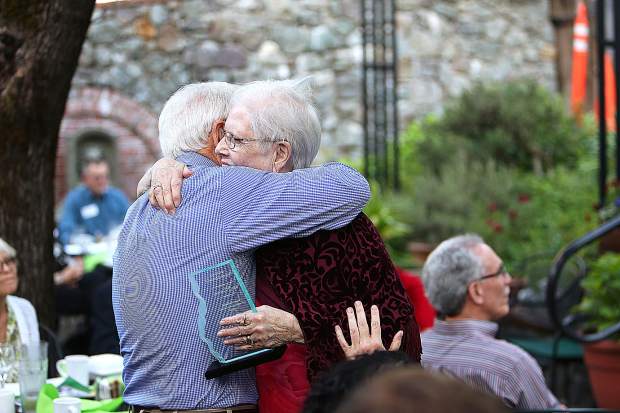Two Sierra Roots community members greeting each other with a hug at an outdoor gathering.